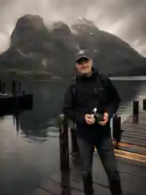 Dan Case on a dock beside a mountain lake